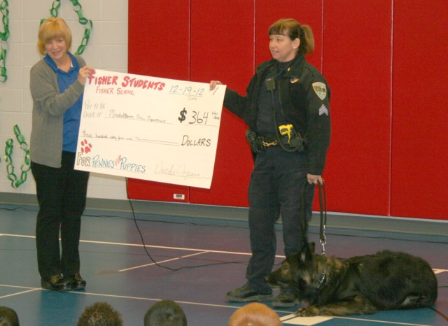 Sgt. Melinda Ruopp and her K-9 partner, Awol, accept a check from principal Vicki Vopava. The Marshalltown Police Department is raising funds to purchase two new K-9 units.