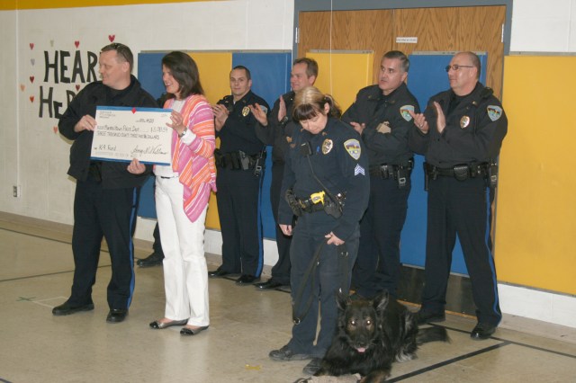Hoglan Principal Amy Williams hands a check to Marshalltown Police Chief Mike Tupper for the penny war her school held in support of the MPD K-9 Unit.